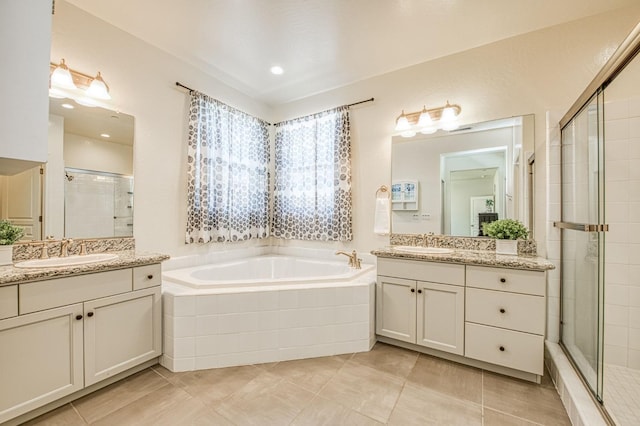 full bathroom featuring a garden tub, a stall shower, two vanities, and a sink