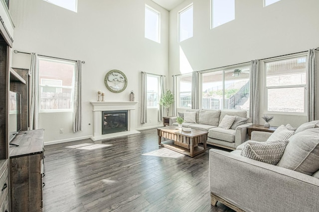 living area featuring a glass covered fireplace, plenty of natural light, and a towering ceiling