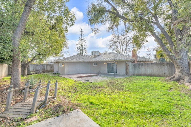 back of house with a chimney, a patio area, stucco siding, a lawn, and a fenced backyard
