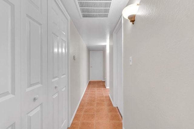 hallway featuring baseboards, visible vents, and light tile patterned floors