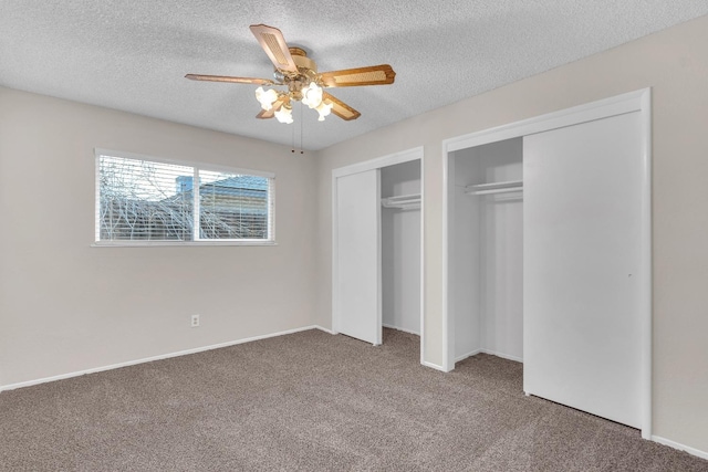 unfurnished bedroom with a ceiling fan, a textured ceiling, carpet, and multiple closets