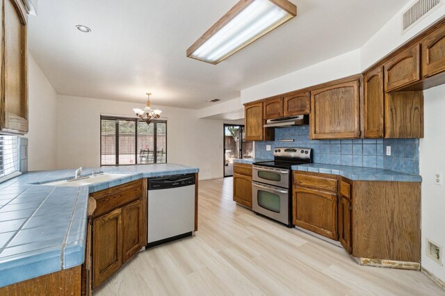 467 E Alluvial Ave Unit 106, Fresno, CA 93720 - kitchen featuring appliances with stainless steel finishes, tile countertops, under cabinet range hood, a sink, and a chandelier