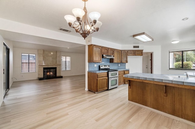 467 E Alluvial Ave Unit 106, Fresno, CA 93720 - kitchen featuring range with two ovens, under cabinet range hood, brown cabinetry, a chandelier, and tile countertops