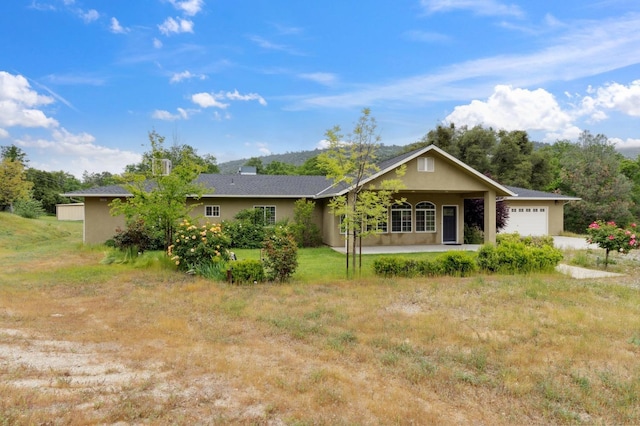 ranch-style home featuring a front yard, a garage, stucco siding, and covered porch