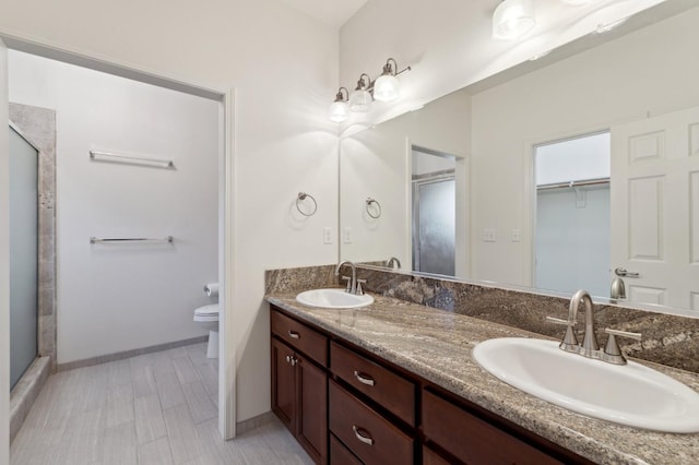 full bathroom with double vanity, toilet, a shower stall, and a sink