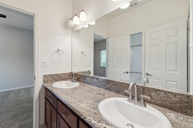 bathroom with double vanity, visible vents, and a sink