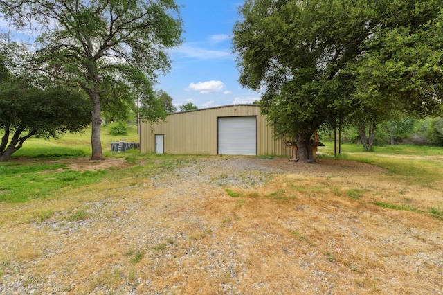 exterior space with an outdoor structure, a detached garage, and driveway