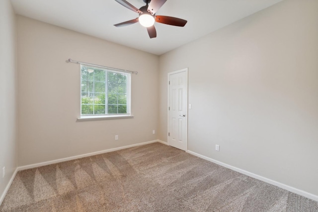 carpeted spare room with ceiling fan and baseboards