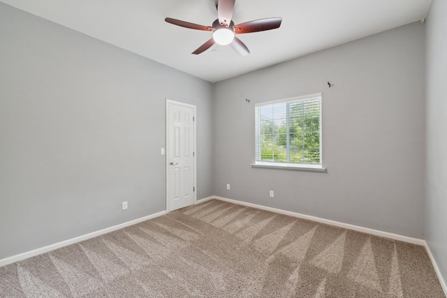 empty room with a ceiling fan, carpet floors, and baseboards