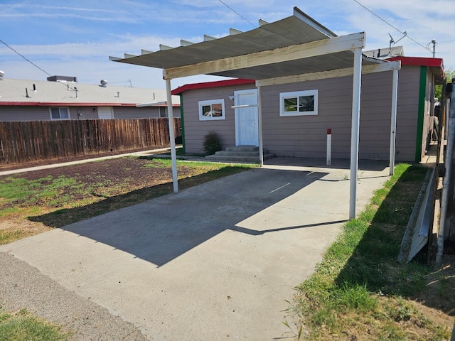 back of property featuring fence, a carport, entry steps, and driveway