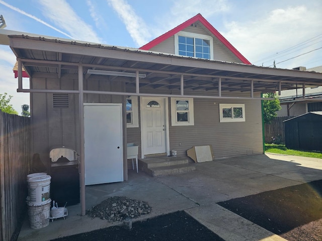 exterior space with fence, a storage unit, a carport, and an outbuilding