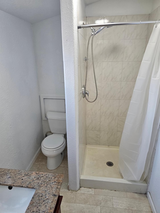 bathroom featuring toilet, a stall shower, and tile patterned floors