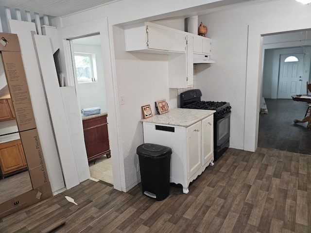 kitchen with under cabinet range hood, black gas stove, dark wood-style flooring, and white cabinetry
