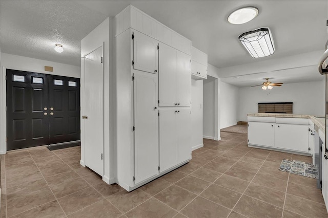30 S Cambridge Dr, Lemoore, CA 93245 - kitchen with light tile patterned floors, a ceiling fan, white cabinetry, a textured ceiling, and baseboards
