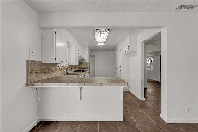 30 S Cambridge Dr, Lemoore, CA 93245 - kitchen with a peninsula, tile counters, a sink, and dark tile patterned floors