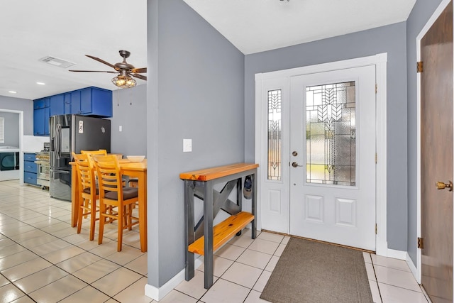 foyer with light tile patterned floors, washer / dryer, a ceiling fan, visible vents, and baseboards