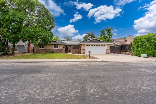 ranch-style house featuring driveway, roof mounted solar panels, fence, a front lawn, and a garage