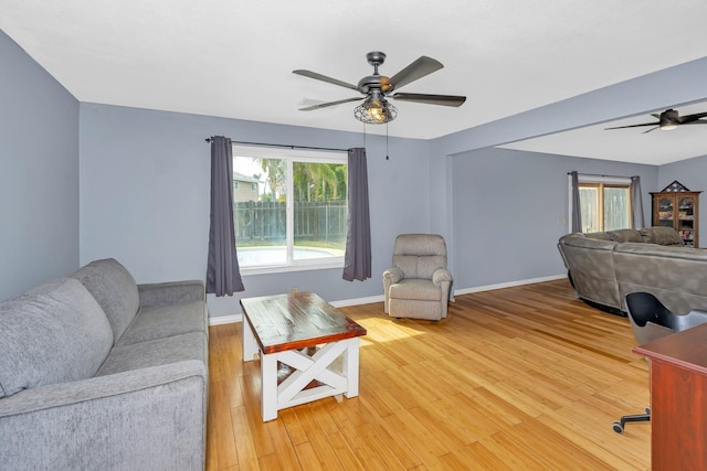 living area with light wood finished floors, ceiling fan, and baseboards