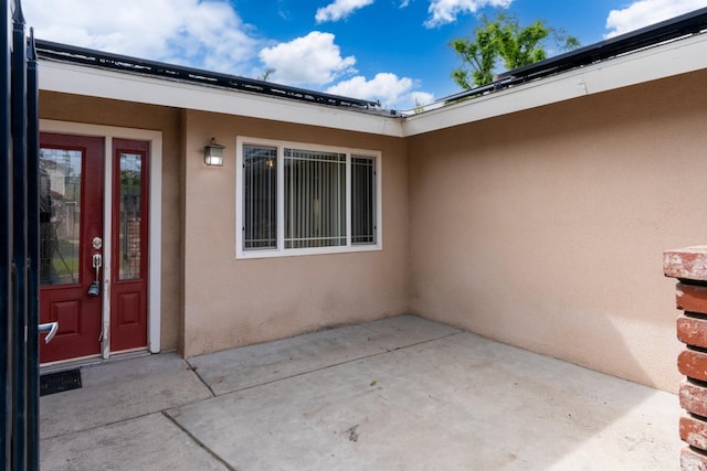 entrance to property featuring a patio and stucco siding