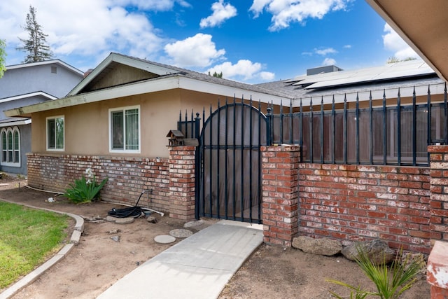 view of front of property with stucco siding, a gate, brick siding, and a fenced front yard