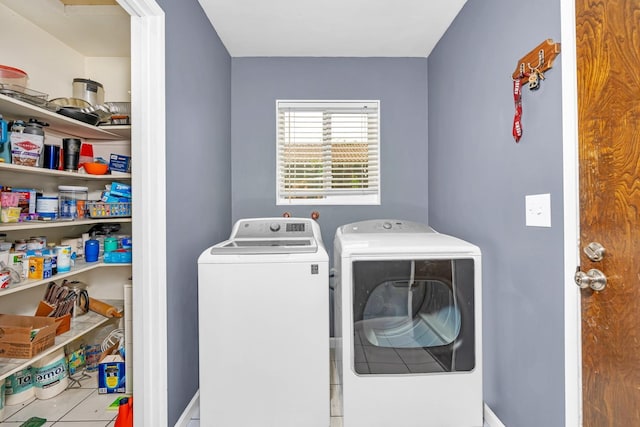 clothes washing area with washing machine and dryer, tile patterned flooring, and laundry area