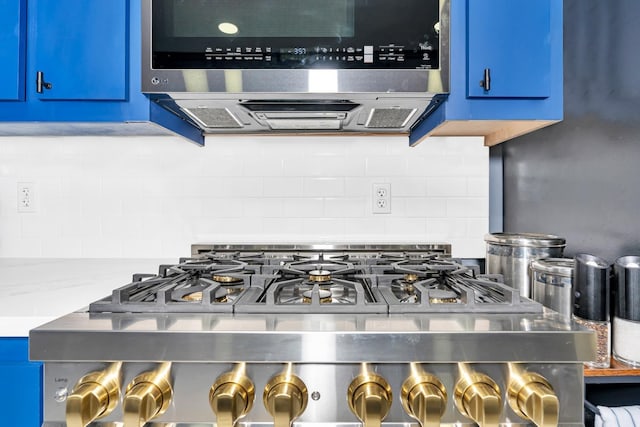 interior details featuring decorative backsplash, stainless steel microwave, and blue cabinets
