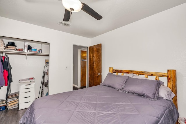 bedroom with wood finished floors, visible vents, a ceiling fan, and a closet