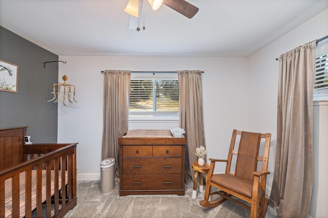 bedroom featuring a crib, ceiling fan, baseboards, and carpet floors