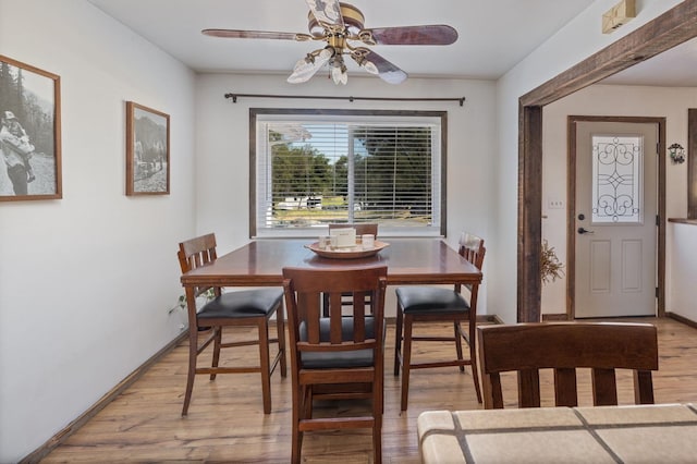 dining room featuring ceiling fan, baseboards, and light wood-type flooring