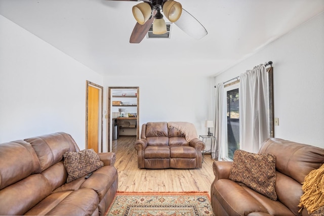 living room featuring visible vents, wood finished floors, and a ceiling fan