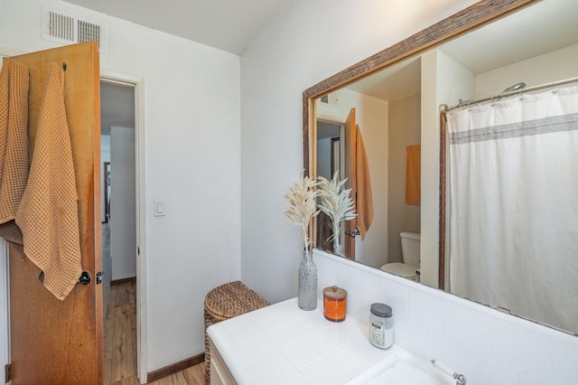 bathroom with wood finished floors, visible vents, toilet, and a shower with curtain