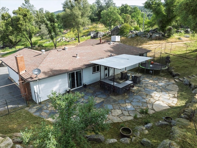 back of house featuring a trampoline, a fenced backyard, central air condition unit, and a patio area