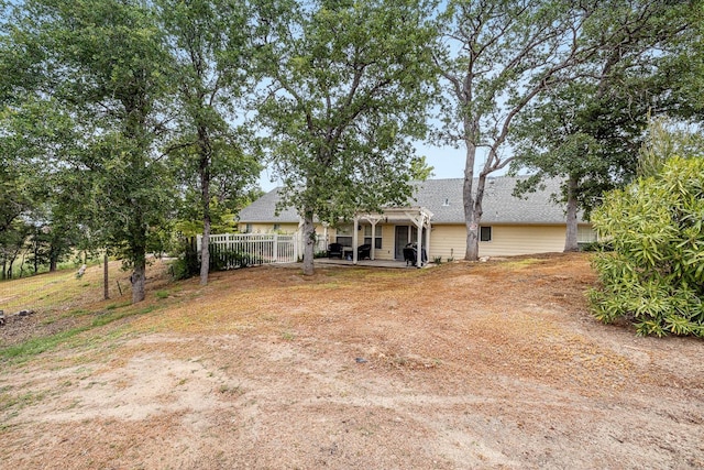 rear view of house featuring a patio, fence, and roof with shingles
