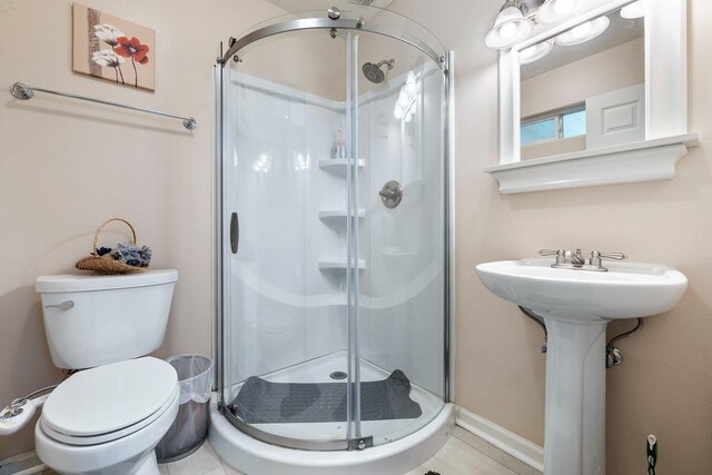 full bathroom featuring toilet, a stall shower, and baseboards