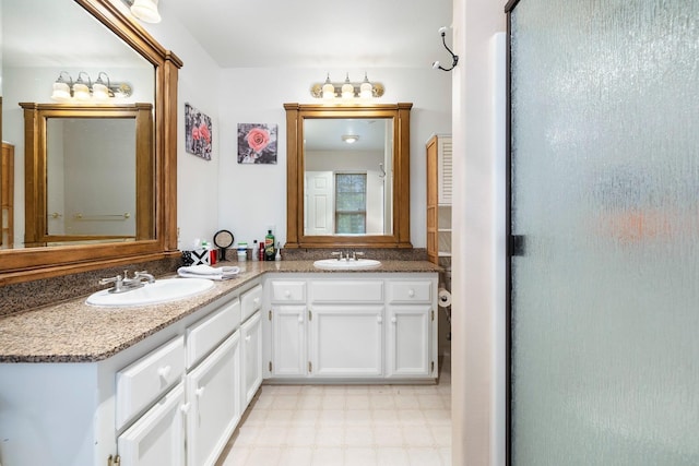full bath with a shower with shower door, double vanity, a sink, and tile patterned floors