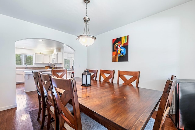 dining room featuring dark wood-style flooring and arched walkways
