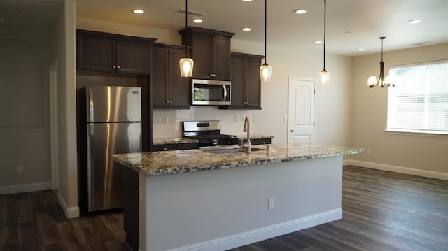 kitchen featuring dark wood-style floors, a kitchen island with sink, stainless steel appliances, dark brown cabinetry, and baseboards