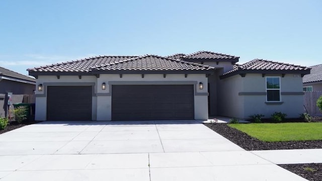 mediterranean / spanish house featuring stucco siding, a tiled roof, concrete driveway, and a garage