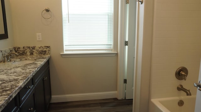 full bathroom with baseboards, wood finished floors,  shower combination, and vanity