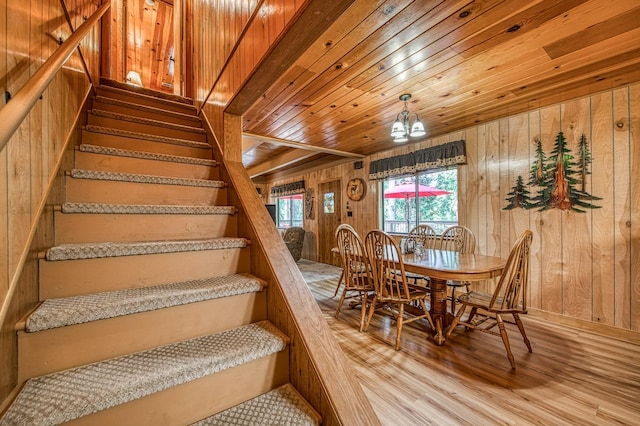 stairs featuring wooden walls, an inviting chandelier, wooden ceiling, and wood finished floors