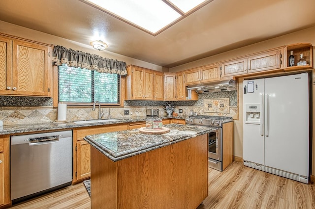 kitchen with a sink, stainless steel appliances, light wood finished floors, and under cabinet range hood
