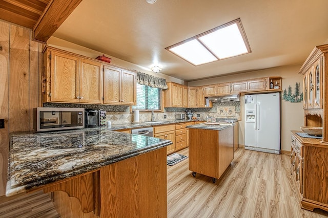 kitchen featuring decorative backsplash, a sink, stainless steel appliances, a center island, and light wood-type flooring
