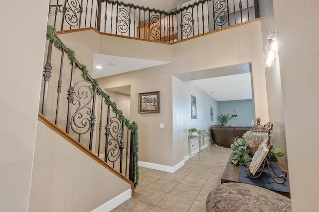 tiled entryway featuring a towering ceiling, stairway, and baseboards