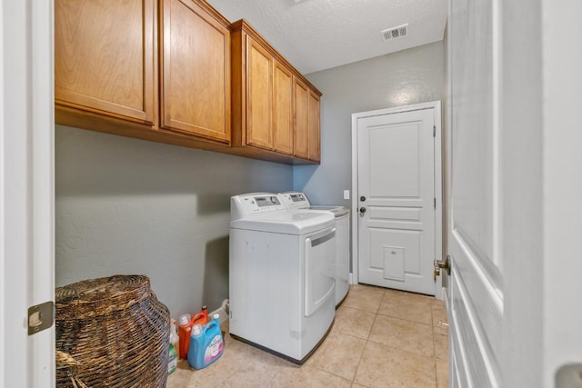 clothes washing area with cabinet space, light tile patterned floors, washing machine and dryer, visible vents, and a textured ceiling