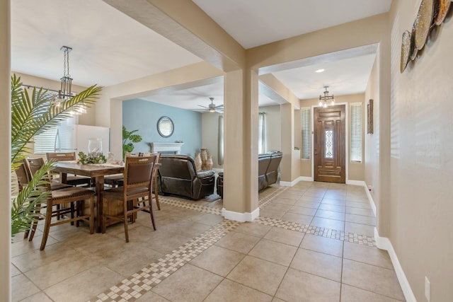 foyer entrance with baseboards, light tile patterned floors, and ceiling fan with notable chandelier