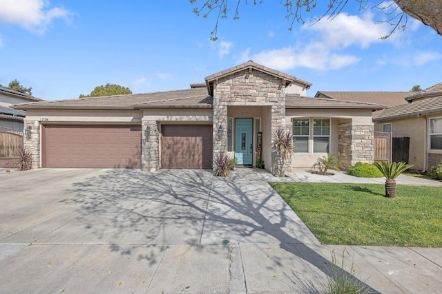 view of front of home with stucco siding, a garage, stone siding, a front yard, and concrete driveway