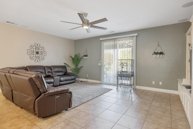 living area with light tile patterned flooring, visible vents, a ceiling fan, and baseboards