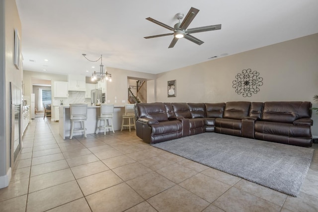 living area with light tile patterned floors, visible vents, recessed lighting, and ceiling fan with notable chandelier