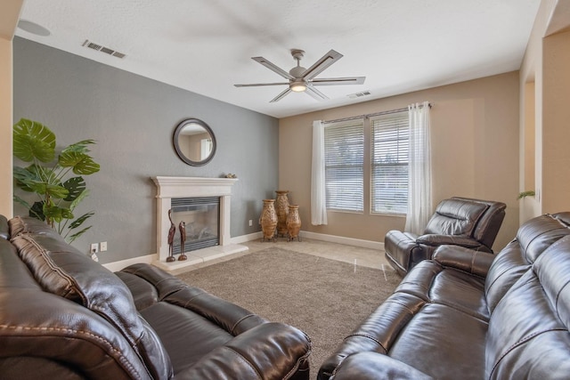 living room featuring visible vents, ceiling fan, baseboards, and a glass covered fireplace