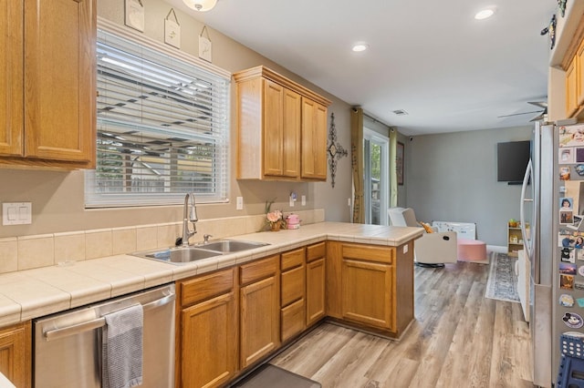 kitchen featuring recessed lighting, appliances with stainless steel finishes, a sink, light wood-type flooring, and a peninsula